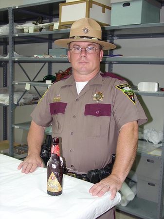 State Trooper Brent Saucerman posing with the antique beer bottle he recently found in the State Capitol. (Photo courtesy South Dakota State Historical Society)